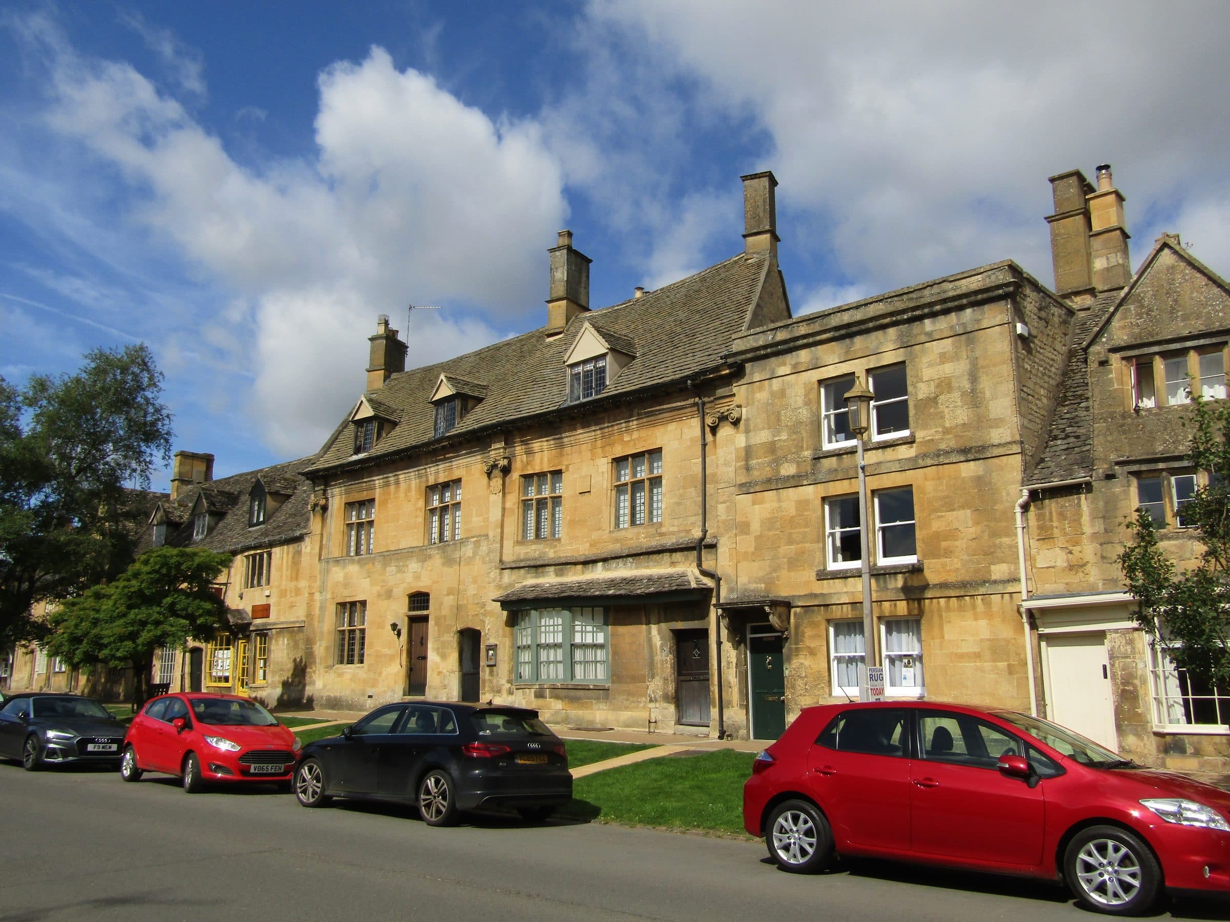 Honey-coloured Cotswold stone houses along the High Street in Chipping Campden under a blue sky.