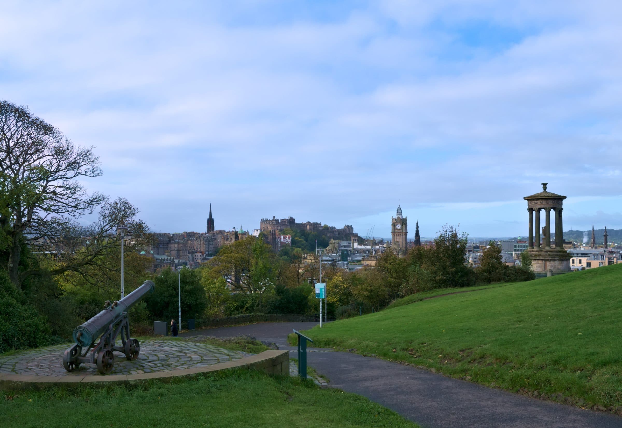 Edinburgh seen from the grass slopes of Calton Hill, with the castle and the Balmoral clock tower on the skyline.